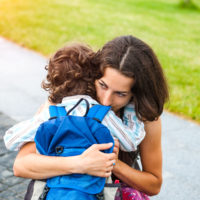 A Woman Is Hugging A Boy.